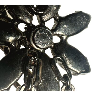 Vintage pair of Butler & Wilson 1980s clip on aurora borealis flower earrings. Close up photo of the Butler and Wilson logo on the back of one earring.