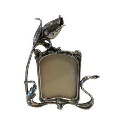 A small modern sterling silver photo frame in the Art Nouveau style. Pretty frame with a single tulip flower coming off to the left side of frame as if to embrace the photo. Hallmarked 925 for sterling silver to the back. Main photo showing frame from the front with the tulip flower to the left.