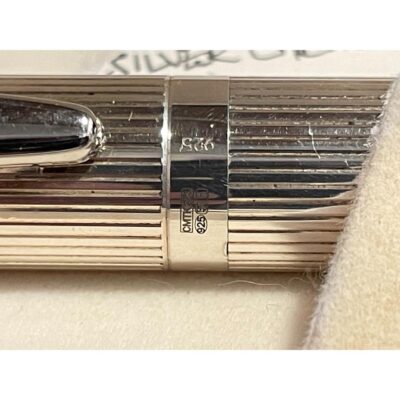A modern 925 sterling silver cartridge pen. A wonderfully stylish silver pen with an enpty cartouche on the cap for personalisation. Comes in original box which has some minor signs of wear. Pen measures 142mm long. Unused cartridge included. Close up photo of the hallmark on the central band of the pen.