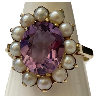 Antique style 9 karat gold ring set with a generously sized oval cut pale purple amethyst to the centre within a seed pearl frame. Full hallmark for Birmingham assay c1992. Ring size P / 7.5. Close up photo of the ring front.