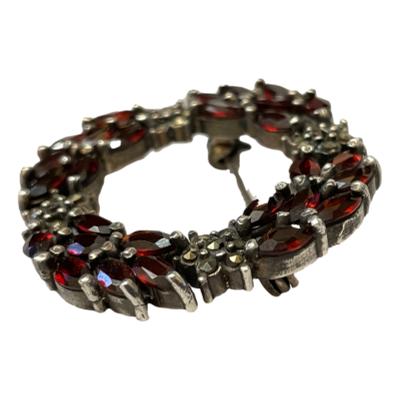 Vintage style sterling silver brooch with garnets and marcasite. Hallmarked 925 for sterling silver to the back. Photo of brooch shown from a side angle.