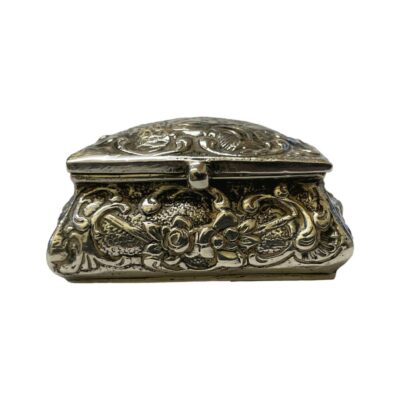 Small vintage casket shaped box in 800 Continental silver. Highly embossed silver work to all 4 sides with a village scene to lid. Looks a little lopsided with right side slightly lower than right. Hinged lid shuts nice and tight although rattles when closed if shaken. Hallmarked 800 to the base. Main photo of box with lid closed and seen from the front.