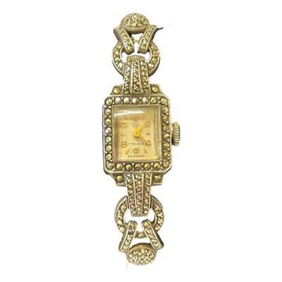 Art Deco cocktail watch in 835 silver with marcasite to the front. Watch face is marked 17 rubis EB Suisse. Worn inscription on the back which is difficult to read - last line reads Brooklyn PA. 835 silver hallmark to the back. Nice watch that keeps good time with clasp in good working order. Watch face is tiny & measures approximately 10 by 8mm. Photo of watch face and marcasite area.