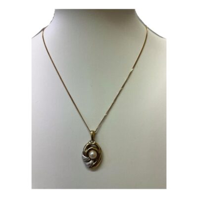 Vintage 9 karat gold pendant with a single pearl & 2 small diamonds. Unusual pendant in yellow and white 9 karat gold with a pearl to the centre and 2 small round cut diamonds in the white gold accent to the side of the pearl. Hallmarked 375 and DIA to pendant bail and 375 to chain clasp. Pendant drop length 25mm and width 15mm. Main photo of necklace on a display stand and shown straight on from the front.