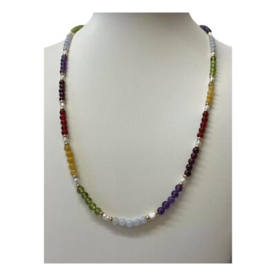 Modern necklace set with multiple semi precious gem stones. Colourful beaded necklace with alternating rows of garnet, amethyst, carnelian, moonstone, peridot & citrine with freshwater pearls and gilt bead separators. Finished with a gilt metal barrel clasp. Main photo of necklace displayed on a stand and seen from the front.