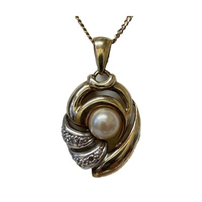 Vintage 9 karat gold pendant with a single pearl & 2 small diamonds. Unusual pendant in yellow and white 9 karat gold with a pearl to the centre and 2 small round cut diamonds in the white gold accent to the side of the pearl. Hallmarked 375 and DIA to pendant bail and 375 to chain clasp. Pendant drop length 25mm and width 15mm. Close up photo of the pendant only.
