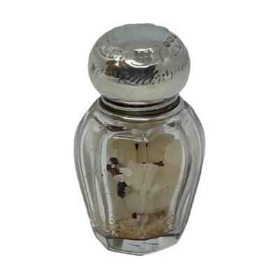 Antique small glass bottle from Boots Pure Drug Company. Small octagonal bottle with sterling silver top which has full hallmark for Birmingham assay c1915. Some contents included - believed to be smelling salts. The top has a few dints which has not affected the visibility of the hallmark. Lovely historic piece from a company still with us today! Main photo of bottle shown from a near eye level angle with some of the contents of old smelling salts visible
