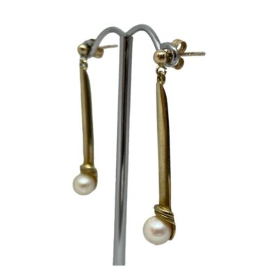 Vintage 9 karat gold and pearl earrings. Stylish and elegant pair of vintage 9 karat gold earrings with a pearl to the ends of each. The gold setting is solid so the earrings hang straight. Hallmarked to both earring pins and 9ct on the butterfly fasteners. Drop length 40mm. Weight 3.7gms. Photo of both earrings displayed on a silver coloured display stand and seen from a slight side angle so one earring is in foreground and other to the back.