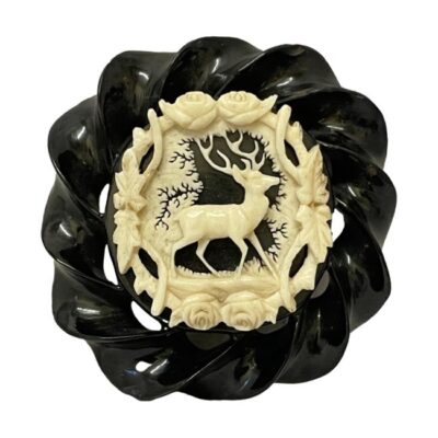 Victorian brooch in carved jet and bone. A substantial sized brooch of beautifully carved Whitby jet with an intricately carved bone detail of a stag applied to the centre. The stag is central to a frame of flora with a tree to the background. This is craftsmanship of the highest order and remains in excellent condition. Believed to be from the Grand Period of the Victorian era c1861-1880. Tube hinge and c clasp fastening with extended pin. Main photo showing brooch looking straight on from the front.