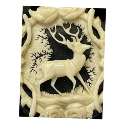 Victorian brooch in carved jet and bone. A substantial sized brooch of beautifully carved Whitby jet with an intricately carved bone detail of a stag applied to the centre. The stag is central to a frame of flora with a tree to the background. This is craftsmanship of the highest order and remains in excellent condition. Believed to be from the Grand Period of the Victorian era c1861-1880. Tube hinge and c clasp fastening with extended pin. Close up photo of the stag and flora frame surrounding him. The intricate detailing of the fine carving is very visible.