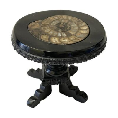 Victorian jet and ammonite table. Antique carved Whitby jet miniature table inlaid with a fine ammonite specimen to the table top. Amazing carved detailing to the jet. The table appears to have had a few repairs during its long life and stands slightly on the skew - this does not detract from the fine quality of this piece. Table top measures 72mm by 62mm, the base measures 50mm by 45mm. Main photo of table seen looking diagonally down at the ammonite in the table top. The table legs are visible below.