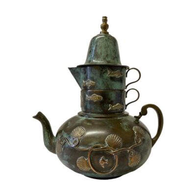 Tea set consisting of 4 stackable pieces. Unusual stackable tea service in mixed metals of stainless steel, copper and brass. The interiors are stainless steel, with verdigris effect outer patina and finished in brass decorations of an underwater theme. The set consists of a tea pot, a cup, a jug and a bell which doubles as a lid for the tea pot. Tea pot measures 185mm long, 135mm wide and 75mm tall. Jug is 105mm long, 64mm wide and 35mm tall. Cup is 85mm long, 64mm wide and 32mm tall. Bell is 74mm in diameter at base and 70mm tall. Main photo of the whole service in stacked mode with tea pot at bottom followed by the cup, jeg then tea pot lid/bell at top