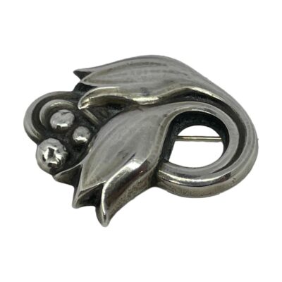 George Jensen tulip brooch. Sterling silver brooch by George Jensen in the form of stylised tulips. Mid century post 1945. Hallmarked Georg Jensen sterling Denmark 100 A to the back. Brooch measures 35mm by 30mm. Main photo showing brooch front with the flower end on the left.