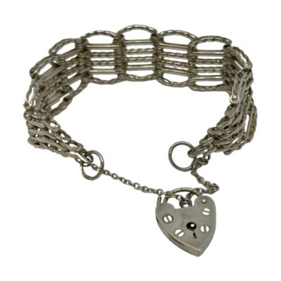 Vintage gate bracelet in sterling silver. 6 bar sterling silver gate bracelet with heart padlock and safety chain. Hallmarked for London assay with makers mark ASJ to back of heart padlock c1976. Lion passant mark on the ring links and to some of the outer bars of the bracelet. Measures approximately 90mm with lock closed and 110mm with lock open and chain extended. Photo of bracelet seen with lock released and safety chain extended. The heart padlock is at the front.