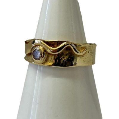 18 karat gold ring set with a small diamond. A nice solid and modernistic 18 karat gold ring set with a small round cut diamond. Full hallmark to inside band. Ring size M / 6. Measures 7mm wide at the ring front. Photo of ring on a cone shaped stand with ring front facing slightly to the left.
