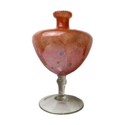 Millefiori art glass c1950s. Striking peach coloured Murano style art glass resembling a poppy head with millefiori pieces scattered along the lower part. Original sticker attached which translated means 'Glass made according to the technique of the masters of Murano'. Stunning in bright light. Measures 140mm in diameter at base, 165mm at widest part and 55mm at mouth. For collection in store only. Main photo of the piece seen from an eye level with a few millefiori pieces visible on the bottom half of the poppy head.