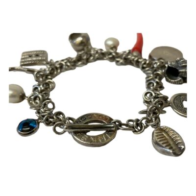 Vintage Links of London Charm Bracelet. A lovely bracelet complete with 12 charms of mixed theme including lucky charms and seashells amongst others. Toggle clasp with Links signature. Measures 185mm long and weighs 44.8 grams. Comes in original Links box which has some wear. Close up photo of the closed bracelet which is laid in a circle with the toggle clasp closed.