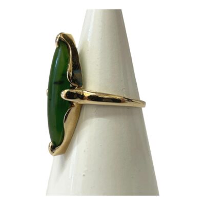 10 karat gold and jade ring. Vintage ring with a long eye shaped jade set in 10 karat gold. Jade size 26mm long and 6mm at widest. 10k hallmark to inside band. Ring size O / 7. Photo of ring on a cone shaped stand and seen with ring front facing left.
