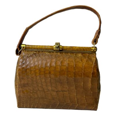1940s French crocodile skin handbag. A stylish vintage French handbag in crocodile skin with a clever shut and clip brass clasp and a small inner pocket to either side. In a well loved condition with some signs of wear. Still very useable and fashionable! Drop length from top of handle 330mm. Main photo of bag shown from one side with the handle extended above.
