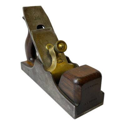 Norris number 13 woodworking plane. A fine example of a quality woodworking tool, this Norris number 13 plane is in excellent condition with very little sign of wear. Pre WWI woodworking plane with rosewood handles and infills. The Rolls Royce of woodworking tools! Heavy item for collection in store only. Main photo of the plane seen posed at a diagonal angle with the rosewood grip at front end in the bottom right corner and rosewood handle end in the top left.