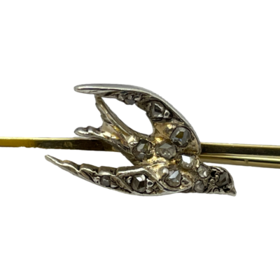 Antique bar brooch with a swallow to the centre. Sweet Edwardian bar brooch in unmarked 9 karat gold with a silver swallow encrusted with rose cut diamonds. The pin closes a little loose and needs attention. Close up photo of the swallow bird hi-lighting the old cut diamonds.
