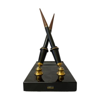Vintage double desk set by Parker. Very chic desk top double pen set. The set consists of 2 Vacumatic fountain pens, one with 14kt gold fine point nib and other with a gilt metal italic nib. The stand, in smooth black granite like stone has a pen rest and an oval space probably for the ink bottle. The whole set is colour coordinated in black and brass with brown to the pen ends which twist off to reveal the filling mechanism. Each pen measures 210mm long. Pen holder slots are 75mm tall. Stand measures 75mm long, 113mm wide and 22mm. Main photo of the stand seen with the pen stand end in the foreground with the original worn Parker label visible in the foreground in yellow.