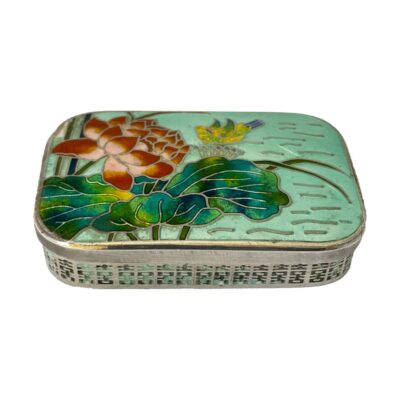 Korean silver box with enamel decoration. An ample sized 980 silver box decorated with enamel to the lid. The enamel decoration is of a beautiful blooming lotus flower with a water fowl in the background. There are some signs of enamel wear especially around the sides of the box. There is also a dint in the top left corner of lid by the lotus flower with some missing enamel and some small cracks in the enamel water to the right. Hallmarked Made in Korea Silver 98% to the base. 78grams. Main photo of box seen from a raised angle looking down at the colourful enamel lid. Part of the side of box is visible.
