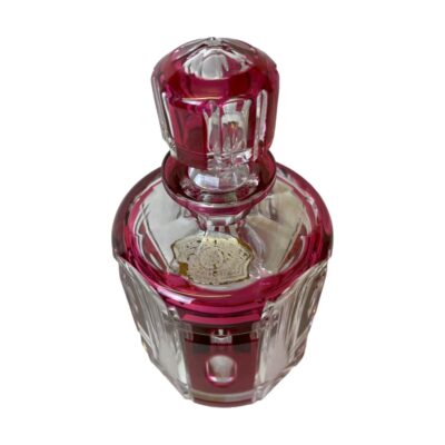 Vintage Val St Lambert bottle with stopper. Beautifully cut crystal bottle in clear and cranberry glass with the clear glass areas all dimpled. Lovely dressing table piece or for storing some special tipple! Signed to the base with original sticky label attached at top. Made in Belgium. Photo of bottle with stopper in place and seen from a raised angle looking diagonally down. The cranberry crystal stipe is in the foreground.