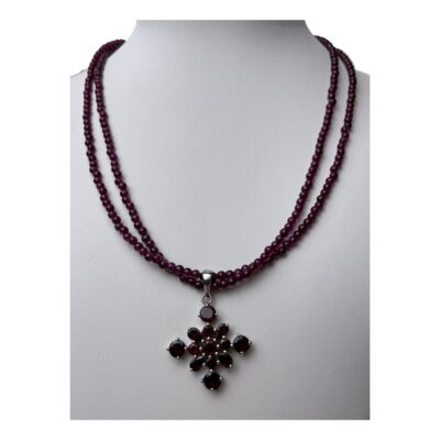 Garnet necklace and pendant in silver. Lovely 2 strand garnet bead necklace with silver clasp and a sterling silver and garnet pendant. The garnet beads on the necklace are almadine in a pink/purple shade and the 4 pointed star shaped pendant has wine red colour garnets. The pendant can be removed if desired. Necklace is slightly adjustable from 450mm to 500mm. Pendant drop length 40mm and width 30mm. Main photo of necklace on a display stand and seen forward facing.