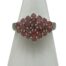 Sterling silver ruby cluster ring. Pretty pink ruby cluster ring set on sterling silver. Total of 23 small round cut pink rubies are set in a diamond shape and each stone separated with silver rod dividers. Ring size O.5 / 7.25. Main photo of ring displayed on a cone shaped stand and seen with ring front forward facing. The cluster of rubies is set with 5 in a vertical row to the centre, 4 either side of this then 3 then 2 at the ends.