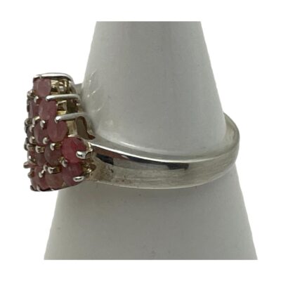 Sterling silver ruby cluster ring. Pretty pink ruby cluster ring set on sterling silver. Total of 23 small round cut pink rubies are set in a diamond shape and each stone separated with silver rod dividers. Ring size O.5 / 7.25. Photo of ring on a cone shaped stand with ring front facing left.