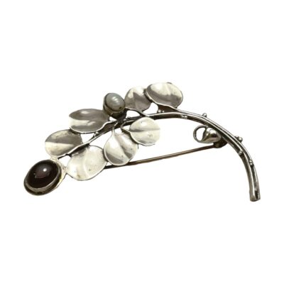 Art Nouveau sterling silver branch brooch. Pretty brooch in the form of a branch with leaves and a single deep red garnet cabochon at the tip and a freshwater pearl mid way. Hallmarked 925 to the back of the brooch on stem. Main photo of brooch seen with garnet end to the left and stalk end to the right. The branch is seen arched like a rainbow.