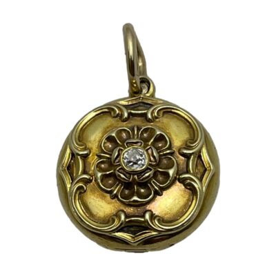 Gold locket with old cut diamond. Very pretty round locket in unmarked yellow gold decorated to the front with a Tudor Rose style design and an old cut diamond to the centre. The original glass remains inside which appears to be completely stuck and may need professional intervention to remove. Drop length from top of bail 2.8mm. Locket weight 7 grams. Main photo of locket seen front facing forward with the bail to the top. The wonderful Tudor Rose like design is evident as is the beautiful old cut diamond to the centre.