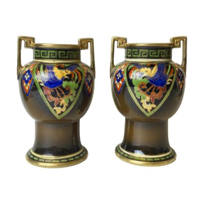 Pair of small 2 handled Noritake vases. Lovely pair of small hand painted Noritake vases with phoenix in flight from the Phoenix & Dragon collection c1890-1921. Greek key design to the handles in gilt and around the rim in green. Both vases in good condition with only minimal gilt wear throughout. Each measures approximately 80mm in diameter at base, 60mm across the mouth. Very slight size difference between the two. Main photo of the two vases displayed side by side from an eye level. The Greek key handles are to either side of each vase and the phoenixes in the triangular panel are facing in towards each other. The base colour of the vases are brown with red, green, yellow and blue decorations and finished with gilt to handles, around base and mouth.
