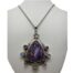 Statement charoite pendant on silver chain. Large striking sterling silver pendant with a substantial charoite stone to the centre and amethyst & rainbow moonstones evenly distributed around it and set in sterling silver. A rainbow moonstone also adorns the unusual bail. Hallmarked 925 to back of pendant and clasp. Pendant measures 88mm long from top of bail and 55mm at widest. Main photo of necklace displayed on a stand with the charoite pendant facing forward. The bail has a rainbow moonstone set on it then sterling silver frame around the triangular pyramid shaped charoite with alternating amethyst and moonstones set around the lower half of the triangle shaped stone.