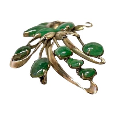 14 karat gold spray brooch with jade. Vintage 14 karat gold spray brooch with jade c1950s. Secure fastening barrel clasp. Hallmarked 14kt to the back. Photo of brooch seen from a side eye level angle with the top of the flower spray in the foreground.