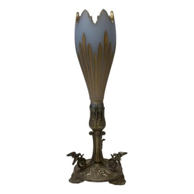 Victorian vase in 2 sections. Very elegant Victorian vase with a detachable opaque glass top and bronzed silver plate base. The opaque glass top, shaped like a crocus flower, is in a pale blue grey with the top rim and indents to the side in gilt. The bronzed silver plate base has 3 feet and is decorated with birds at the end of the scrolls. Glass area of vase measures 265mm tall including the part that slots into base and 80mm in diameter across the top. The base is 180mm tall feet are 132mm apart. Main photo of vase seen from an eye level with 2 of the 3 tripod feet in foreground to left and right and the dip section of glass top visible. (The glass top has a jagged mountain range like edge which goes up and down all round with the gilt decoration matching)