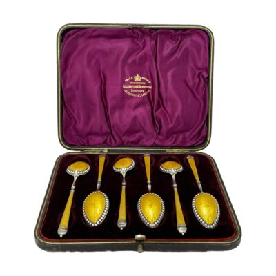 Main photo of the spoons displayed inside the case. All spoons are bowl side down to show the vibrant yellow guilloche enamel. The inside of the case is a royal purple is a very complimentary contrast colour to the yellow of the spoons.
