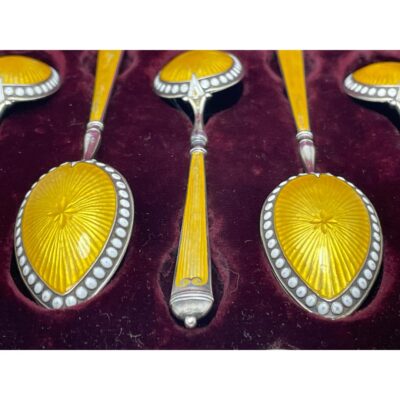 Close up photo of some of the spoons inside the case showing the beautiful vibrant yellow enamel and the white 'jewel' enamel dots.
