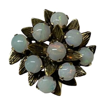 Vintage ring with fiery opals. Eye catching 14 karat gold ring set with 9 small fiery opals in the form of a floral bouquet. Lovely subtle flashes of colour in an otherwise milky opaqueness. Size N / 6.75. Weight 3.6grams. Close up photo of the ring front looking at it straight on. Looks like a bouquet of opal flowers with subtle colour play on each stone.