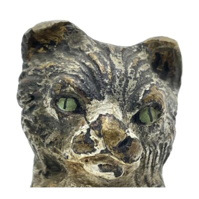 Antique bronze cat in miniature. Sweet little antique cold painted bronze cat which can be displayed in 3 poses: sat upright with front paws raised, on all four paws or on its side in 'rub my tummy' pose. Some wear to the paint. Close up photo of the cats face showing the wear of the paint but also the fine detail of the bronze.