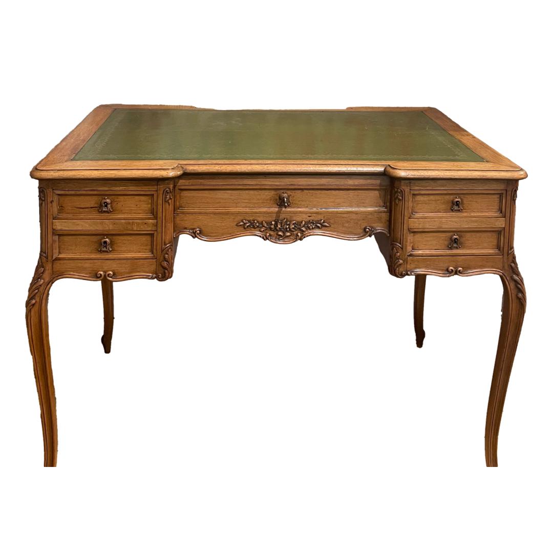 Vintage French writing table. A very attractive French writing table with carved detail, cabriole legs and green tooled leather top. 2 small drawers to the left and right and one drawer to the centre with a single key which locks all drawers. Height 745mm. Desk top measures 995mm by 600mm to the sides and 540mm in the middle. Legs at widest bowed area 1005mm by 595mm. Collect from store only. Photo of writing table seen from the front with beautiful bowed cabriole legs to the front and green tooled leather to the top. 2 small drawers to the left and right one above the other and larger drawer to the centre. An inspiration to get to work if ever there was one! A beautiful piece of French furniture.
