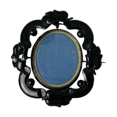 Main photo of locket seen with the pin side to the back. The Whitby jet is carved into an intricate frame with the swivel locket set on a pin at the top and bottom. The locket can only swivel when the pin is opened so the pin side picture is the one closest to the heart!