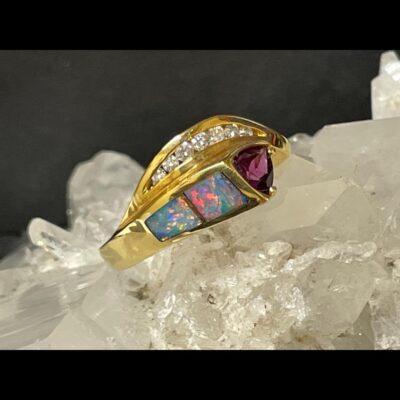 Main photo of ring displayed on a quartz crystal cluster with just the ring front in view. The graduating diamonds are on the top split of the band with the 2 rectangular black opals on the lower band to the left and the cerise coloured garnet at the tip to their right. The ring can of course be worn the other way round. The opals are beautiful in multiple colour flashes