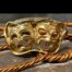 Main photo of ring displayed against a background of copper twists on stone. The ring is seen from the front with the tragedy mask on the left and comedy to its right. The eyes and mouth of both masks are open through. A lovely gift for someone who is wild about the theatre!