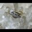 Main photo of ring displayed on some quartz crystal with the ring front forward facing. The platinum setting is 5 circular short tubes with the setting for the diamonds in a star shape.