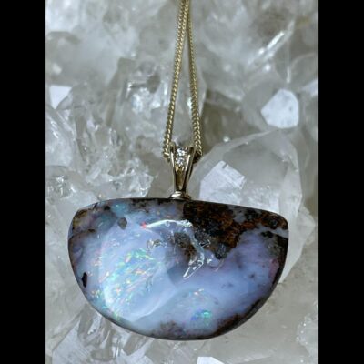 Close up photo of pendant shown displayed on top of a cluster of quartz crystal.