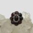 Main photo of ring displayed on a cluster of quartz crystal and shown with ring front forward facing. The garnets are a beautiful deep red colour which is enhanced against the quartz crystal and pale grey background.