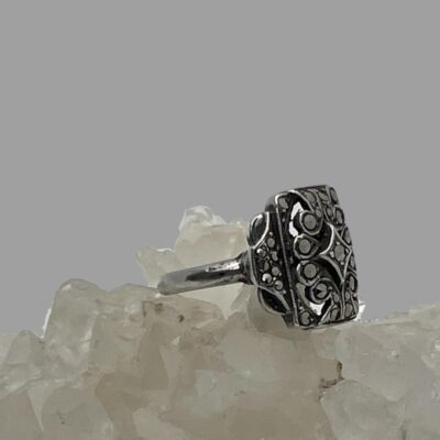Photo of ring displayed on top of some quartz crystal with the ring front facing right.