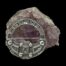 Main photo of brooch shown leaning up against a cluster of natural amethyst with the brooch front forward facing. The safety chain and pin is hidden behind the brooch so only the brooch front is visible with the Celtic signs clearly on display.